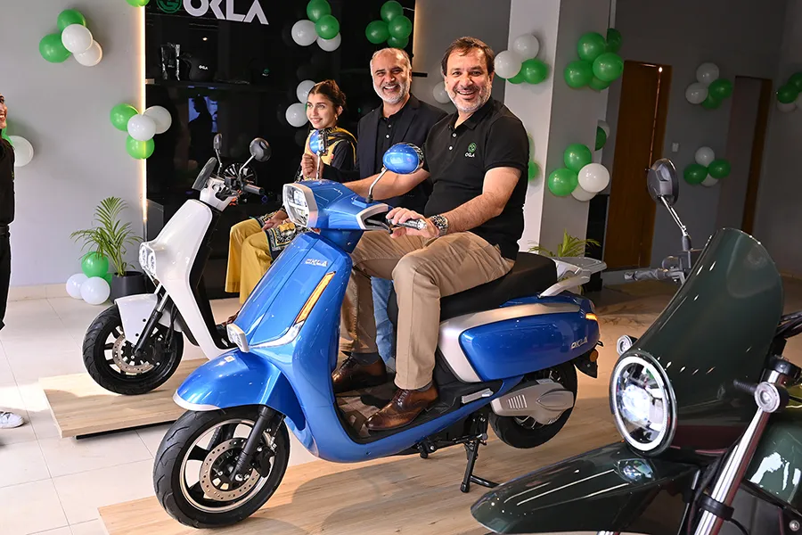 Corporate executives posing with OKLA electric scooters at an e-mobility showroom launch event.